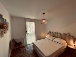 ein Schlafzimmer mit einem Bett, einem Kronleuchter und einem Fenster in der Unterkunft L'océan, T3 neuf 300m de la mer classé 3 étoiles in Saint-Jean-de-Monts