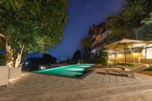 a swimming pool at night with an umbrella and benches at Gracian Villa in Kandy