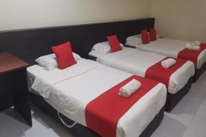 three beds with red and white pillows in a room at Q Hotel Temerloh in Temerloh