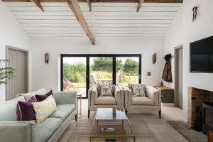 a living room with two couches and a tv at Linseed Barn- Stamford Holiday Cottages in Stamford