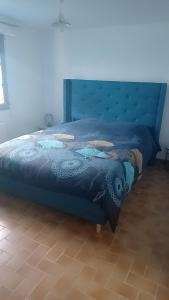 uma cama azul num quarto com piso em madeira em Petite maison ploufragan em Ploufragan
