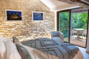 a bedroom with a bed and a stone wall at Hors-série en Périgord in Millac +40 photos