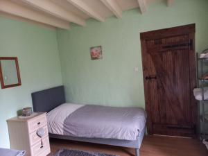 - une petite chambre avec un lit et une porte en bois dans l'établissement Les Deux Sapins, à La Châtre-Langlin