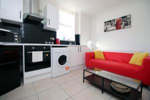a living room with a red couch and a washing machine at Modern 2 Bedroom Flat in Robert st, Swansea in Swansea