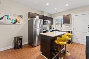 a kitchen with a stainless steel refrigerator and yellow bar stools at Stylish and Comfortable 1-BR in the Heart of Detroit in Detroit