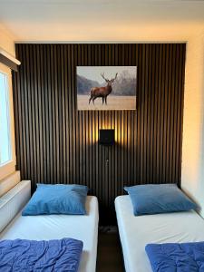 two beds in a room with a picture of a deer on the wall at Gehele Bungalow Simpelveld op een park in Simpelveld