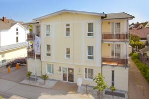 un grand bâtiment blanc avec des balcons sur une rue dans l'établissement zentral aber ruhig, Balkon, gratis Nutzung vom AHOI Erlebnisbad und Sauna in Sellin - Villa Elisenhof FeWo 2, à Göhren