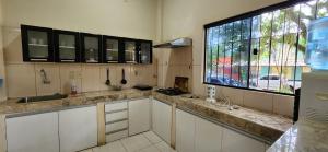 uma cozinha com armários brancos e uma grande janela em Casa duplex en Área 4 CDE em Ciudad del Este
