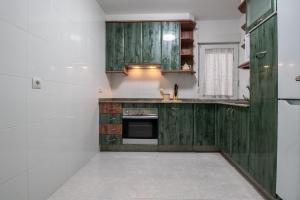 uma cozinha com armários de madeira verde e um fogão em O sete dos Soportais em Pontevedra
