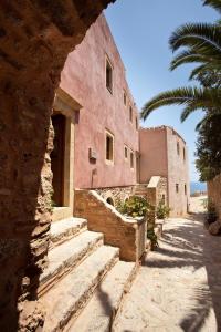 a pink building with stairs and a palm tree at Theophano Art Hotel in Monemvasia