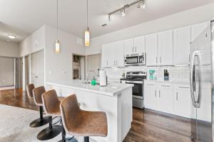 a kitchen with white cabinets and bar stools at Spacious 2BR King Bed Suites Close to Downtown and Airport in Austin