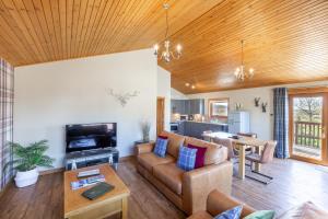 a living room with a couch and a table at Mountain Ash Lodge with Hot Tub in Cupar