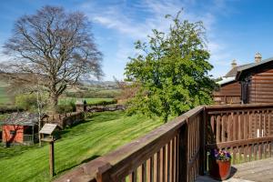 a deck with a wooden fence and a yard at Mountain Ash Lodge with Hot Tub in Cupar
