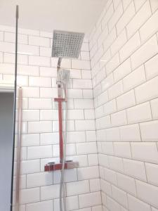 a shower with a red hose in a white tiled bathroom at Beautiful 2 Bedroom Flat in Frampton Street in London