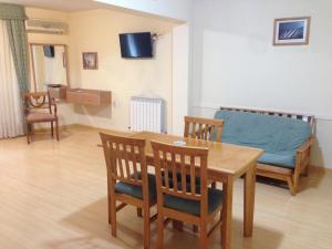 sala de estar con mesa, sillas y sofá en Cóndor Suites Apart Hotel en Mendoza
