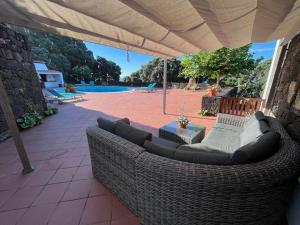 un sofá sentado bajo una sombrilla en un patio en Casa do Ananas, cliff-top/ocean-front villa, Pico en Lajes do Pico