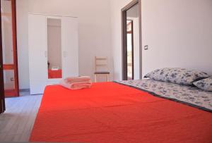 1 dormitorio con cama roja y manta roja en Casa Basilio con bellissima terrazza vista isole, en Lipari