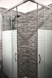 una ducha con puertas de cristal en una habitación en Casa Basilio con bellissima terrazza vista isole, en Lipari
