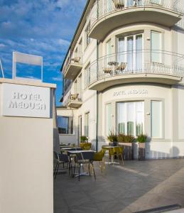 Hotel Medusa في ليدو دي كامايوري: فندق فيه طاولات وكراسي امام مبنى