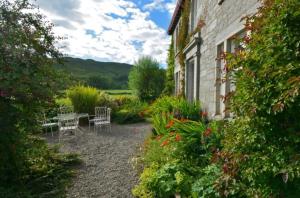 a garden with a table and chairs next to a building at Blarcreen in Oban