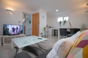 ein Wohnzimmer mit einem Sofa, einem TV und einem Tisch in der Unterkunft Sealock Mews by Property Promise in Cardiff