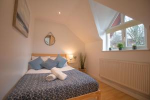ein Schlafzimmer mit einem Bett mit blauen Kissen und einem Fenster in der Unterkunft Sealock Mews by Property Promise in Cardiff