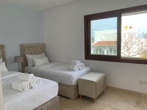 a hotel room with two beds and a window at Villa Jasmin 15 in M'diq