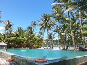 uma piscina com palmeiras e uma praia em White Dragon Sea View Villa em Ko Chang