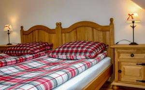 a bed with a red and white plaid blanket and two pillows at Storczykowe Wzgórze in Paszowice