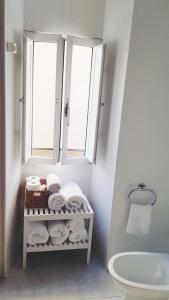 baño con 2 ventanas y estante con toallas en Casa pequeña y acogedora en casco histórico, en Pobra do Caramiñal