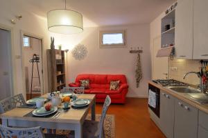 een keuken en een woonkamer met een tafel en een rode bank bij Casa Peppa in Lazise