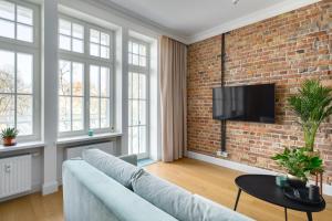 un soggiorno con divano e muro di mattoni di Apartament Aleja 22 a Poznań