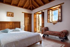 a bedroom with a bed and a chair and windows at Theophano Art Hotel in Monemvasia