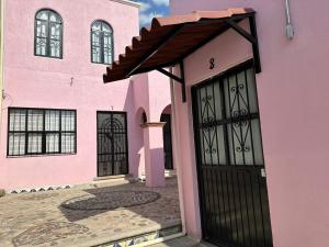 uma casa cor-de-rosa com uma porta preta em Casa Malva Sweet Stay em Guanajuato