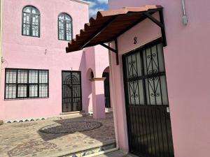 a pink house with a black door at Casa Malva Sweet Stay in Guanajuato