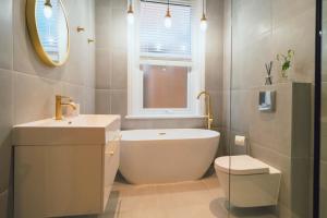 een badkamer met een bad, een wastafel en een toilet bij The Milkmans Residence in Bournemouth