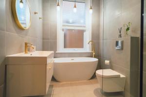 a bathroom with a tub and a sink and a toilet at The Milkmans Residence in Bournemouth