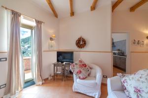 a living room with a white couch and a television at Amalfi Coast Donna Carmela Apartment Pontone holiday house in Scala