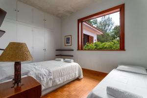 1 Schlafzimmer mit 2 Betten und einem Fenster in der Unterkunft Aconchegante Sítio na Serra com piscina em Itaipava in Itaipava