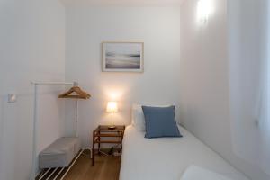 a white bed with a blue pillow and a lamp at FishermenApartments - Carcavelos 1 in Carcavelos