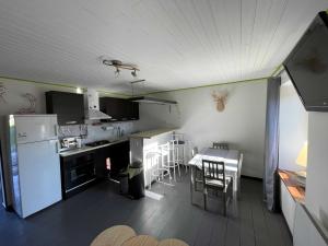 cocina con nevera blanca y mesa con sillas en LE SOULAQUET, en Soulages-Bonneval