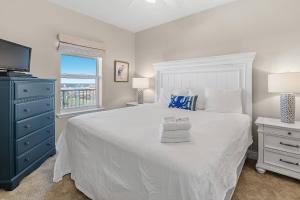 a bedroom with a white bed with a blue dresser and a window at Marlin Key 4F in Orange Beach