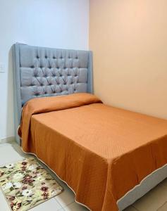 - une chambre avec un lit doté d'un couvre-lit orange et d'un tapis dans l'établissement Casa Daniel confortable, à Palenque