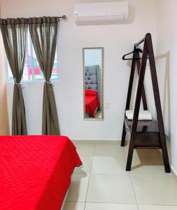 Cette chambre blanche comprend un lit rouge et un miroir. dans l'établissement Casa Daniel confortable, à Palenque
