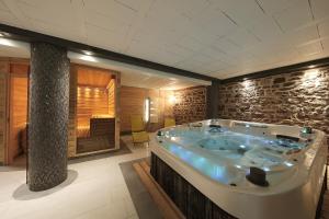 a jacuzzi tub in a room with a stone wall at Le Domaine du Verger, Chambres et SPA prive in Osenbach