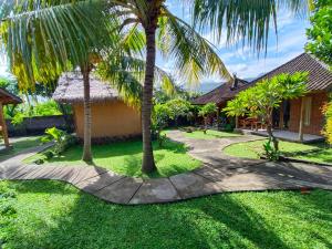 a walkway in front of a house with palm trees at Menjangan View in Banyuwedang