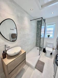 a bathroom with a sink and a shower with a mirror at The Nook - Cosy coastal retreat near Sandbanks in Poole