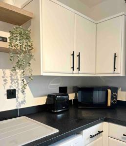 a kitchen with white cabinets and a microwave at The Nook - Cosy coastal retreat near Sandbanks in Poole