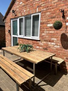 a wooden picnic table in front of a brick wall at Beautiful Bijou Bungalow in Gloucester