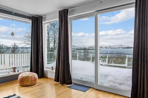 a living room with large windows and a view of the water at Central Panoramic Retreat in Tromsø